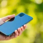 Téléphone Fairphone 6 en main avec fond vert.