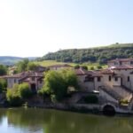 Pont médiéval sur rivière, maisons anciennes, nature verdoyante.