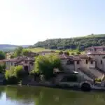 Pont médiéval sur rivière, maisons anciennes, nature verdoyante.