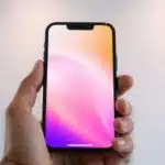 iPhone 13 dans une main, écran allumé