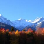 Paysage d'automne avec neige en altitude et ciel bleu.