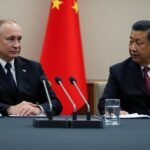 Poutine et Xi Jinping discutent discrètement autour d'une table.