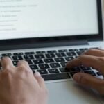 Mains tapant sur un clavier d'ordinateur portable dans un forum.