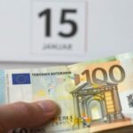 Main de français tenant des billets en euros.