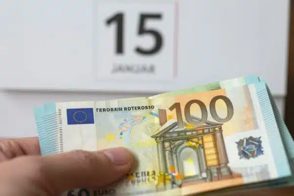 Main de français tenant des billets en euros.