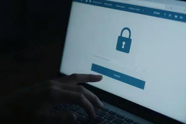 Main de pirate informatique sur un clavier devant un écran