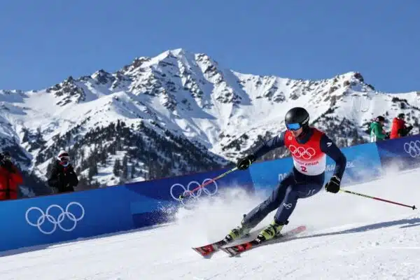 Jeux olympiques Milano-Cortina 2026 : montagnes enneigées et athlète en action.